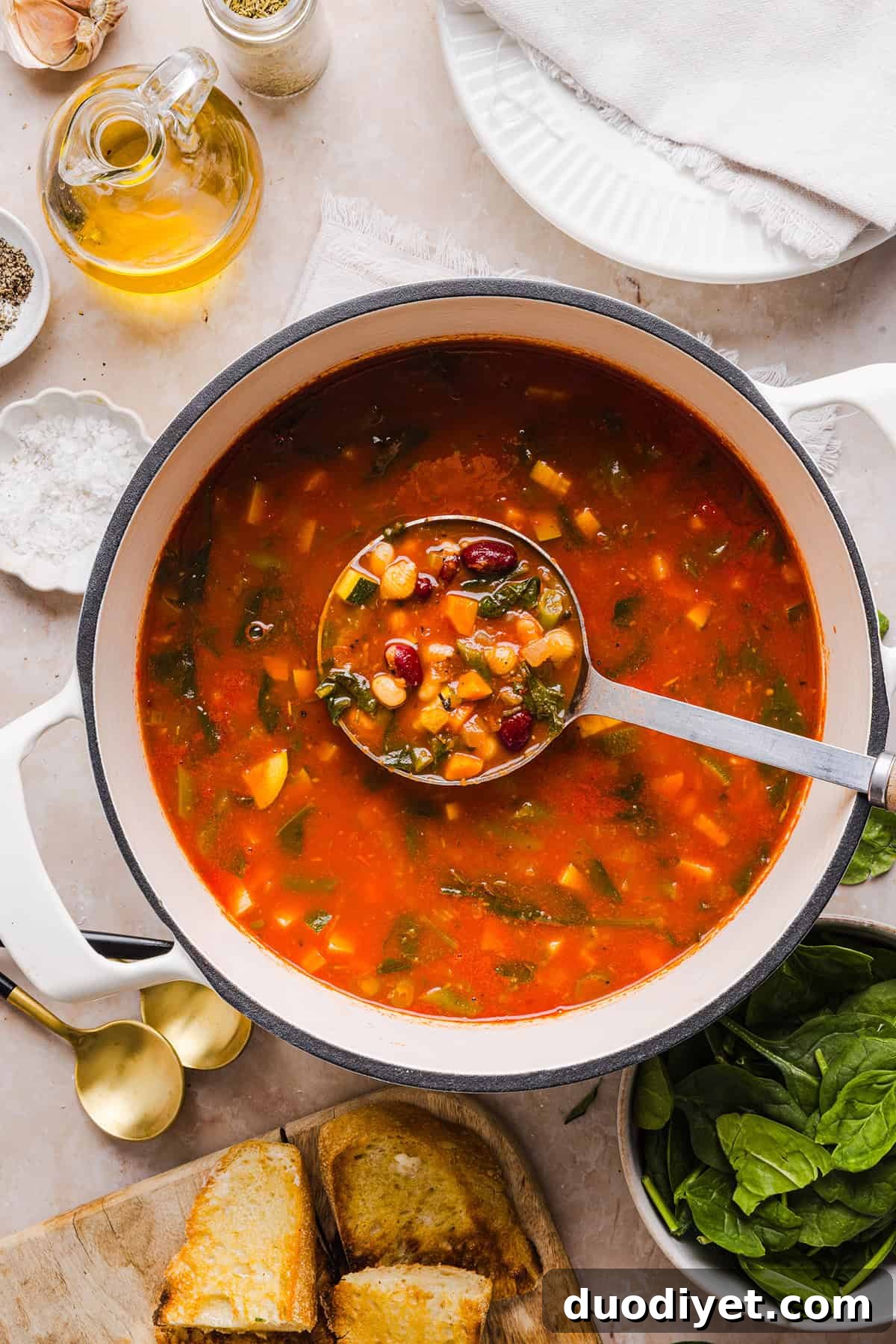 Spoon lifting vegetables from a pot of minestrone
