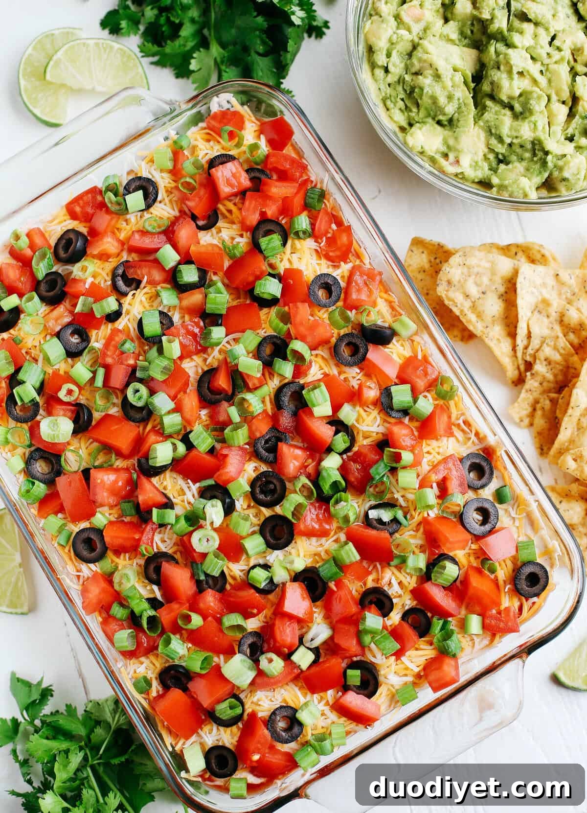 Healthier 7 Layer Spicy Taco Dip made with Greek yogurt, hummus, fresh guacamole, chunky salsa, homemade taco seasoning and fun toppings