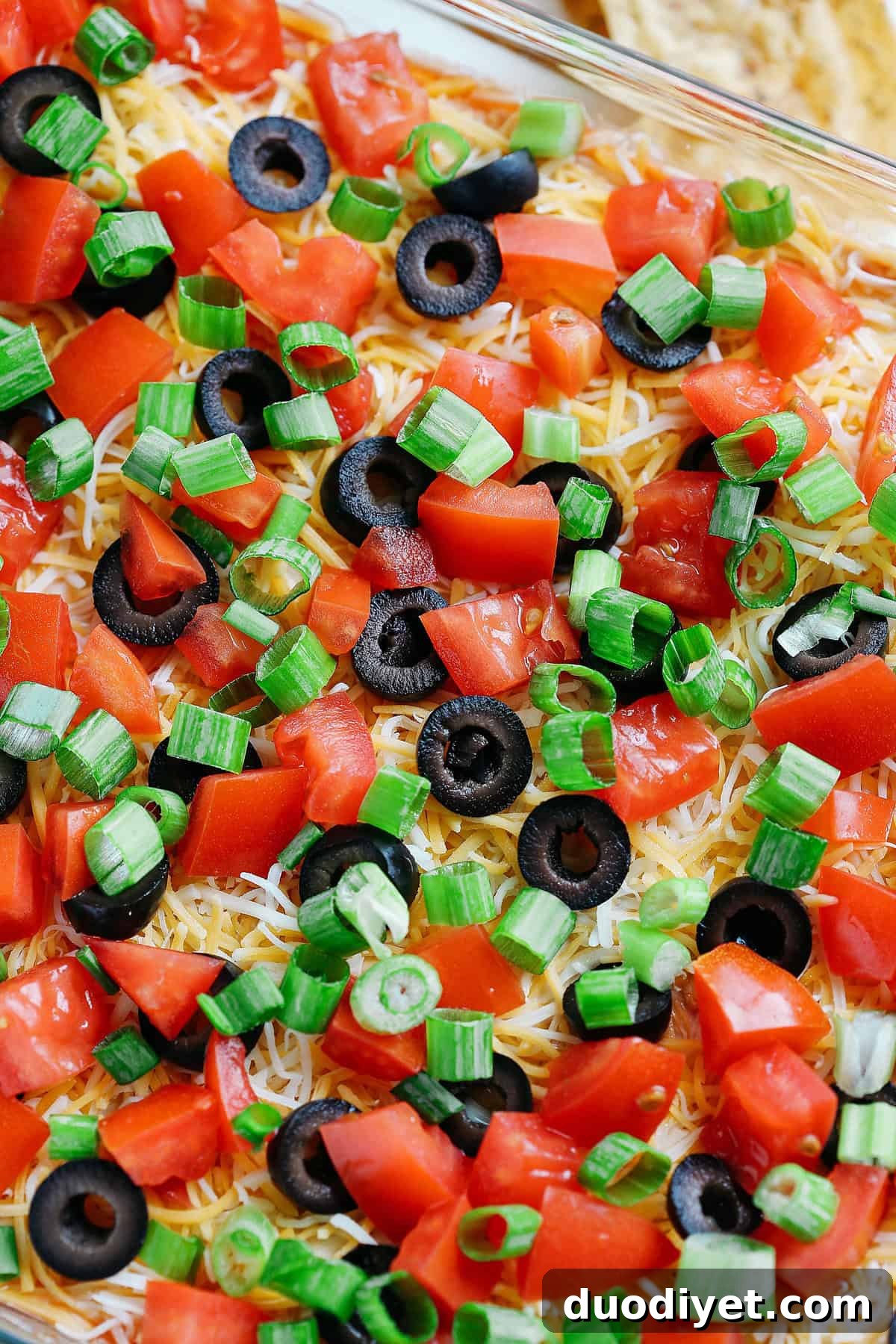 Healthier 7 Layer Spicy Taco Dip made with Greek yogurt, hummus, fresh guacamole, chunky salsa, homemade taco seasoning and all the fun toppings! Super easy to make and always a crowdpleaser!