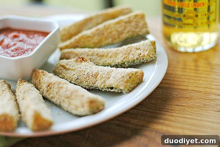 Basket of golden-brown zucchini sticks with marinara