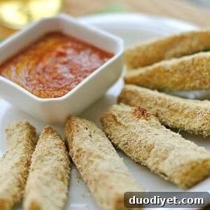 Plated zucchini sticks with sauce in a small bowl