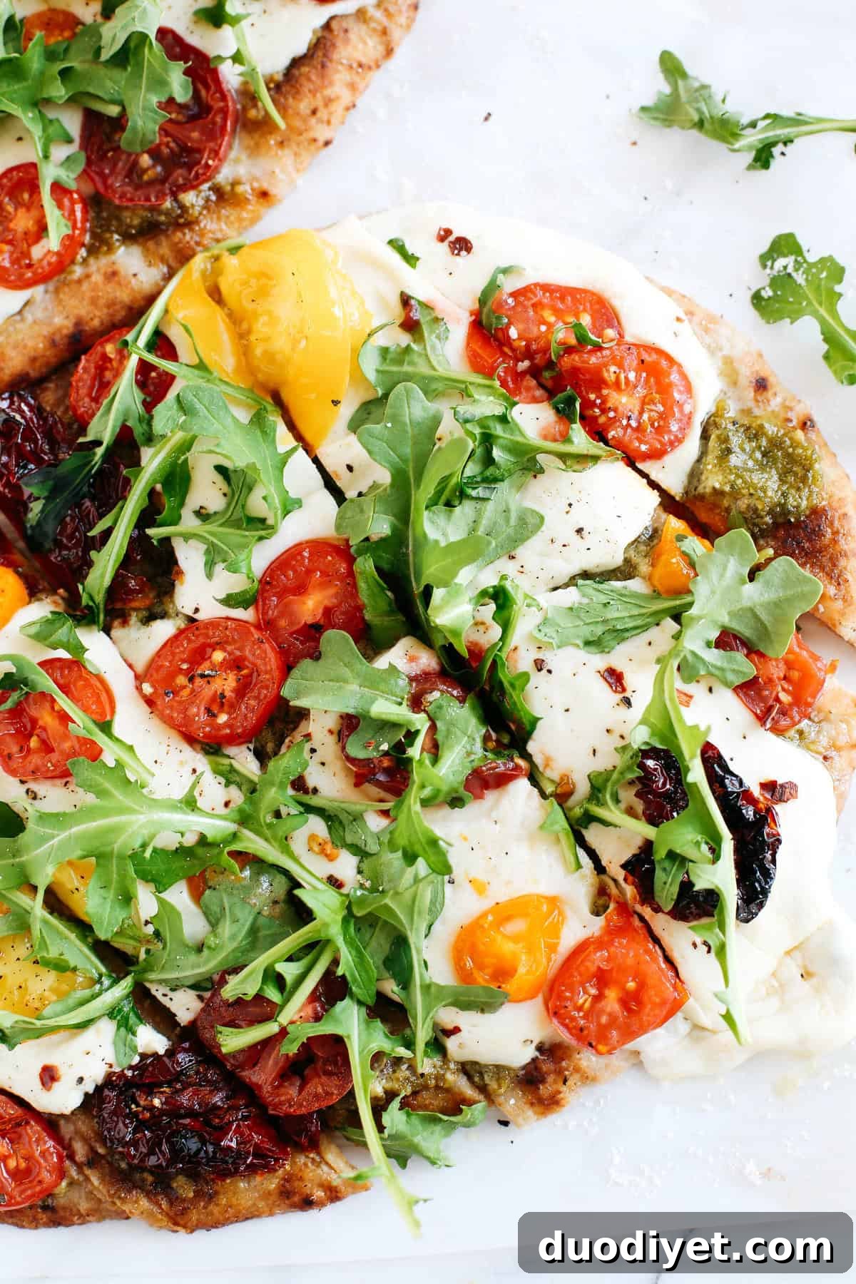 EASY garlicky pesto flatbread pizzas full of fresh tomatoes, basil and arugula for a flavorful weeknight dinner that can be ready in just 15 minutes!