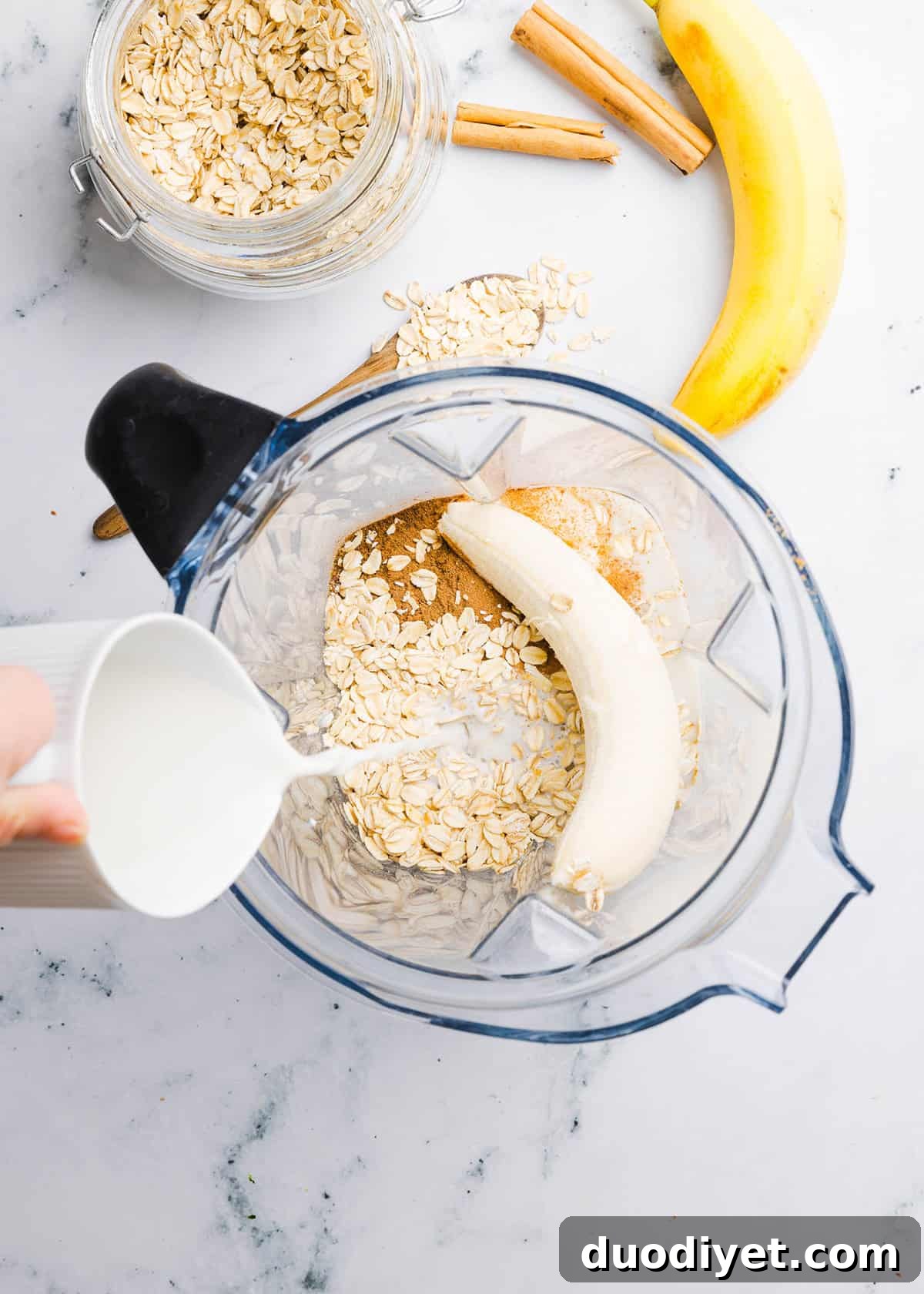Creamy Banana Oat Breakfast Smoothie 4 Two jars of banana oat smoothie on a wooden board.