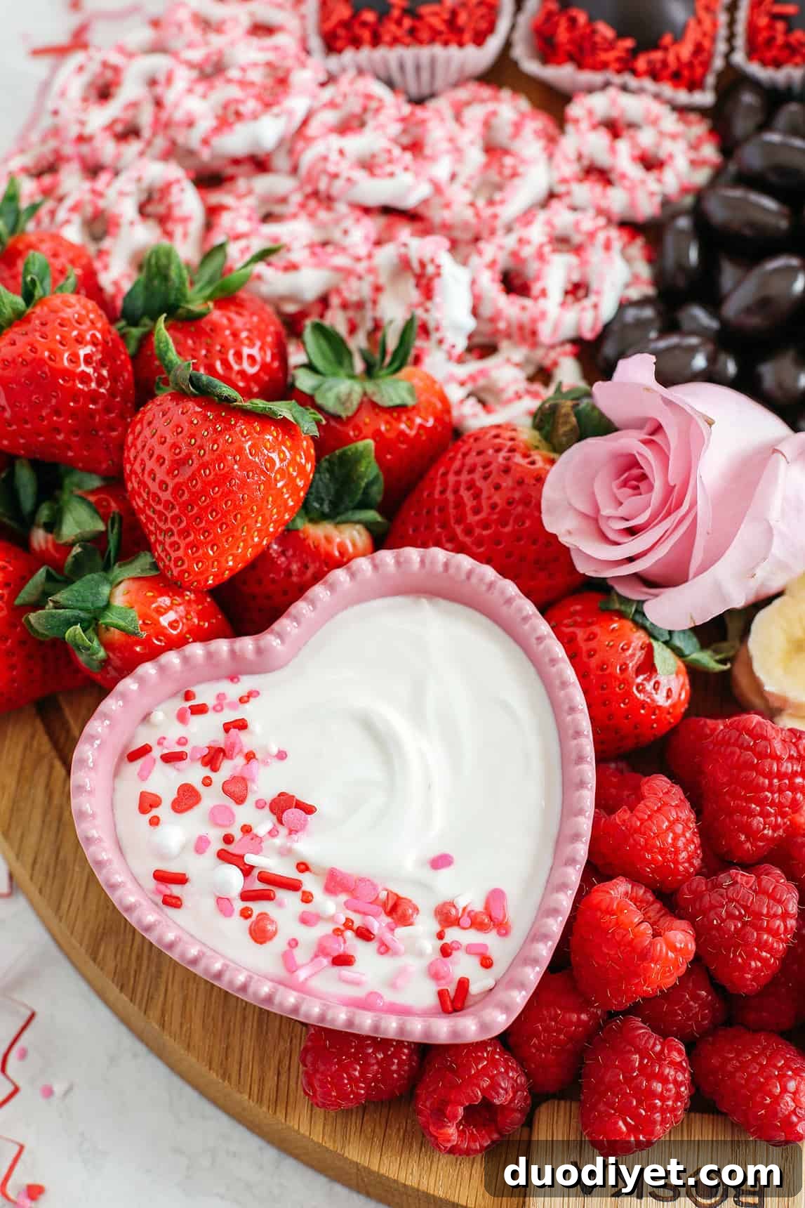 Celebrate Valentine's Day with a fun and festive dessert board made with healthier options like yogurt-dipped pretzels, chocolate covered almonds, fresh fruit and a honey yogurt dipping sauce!