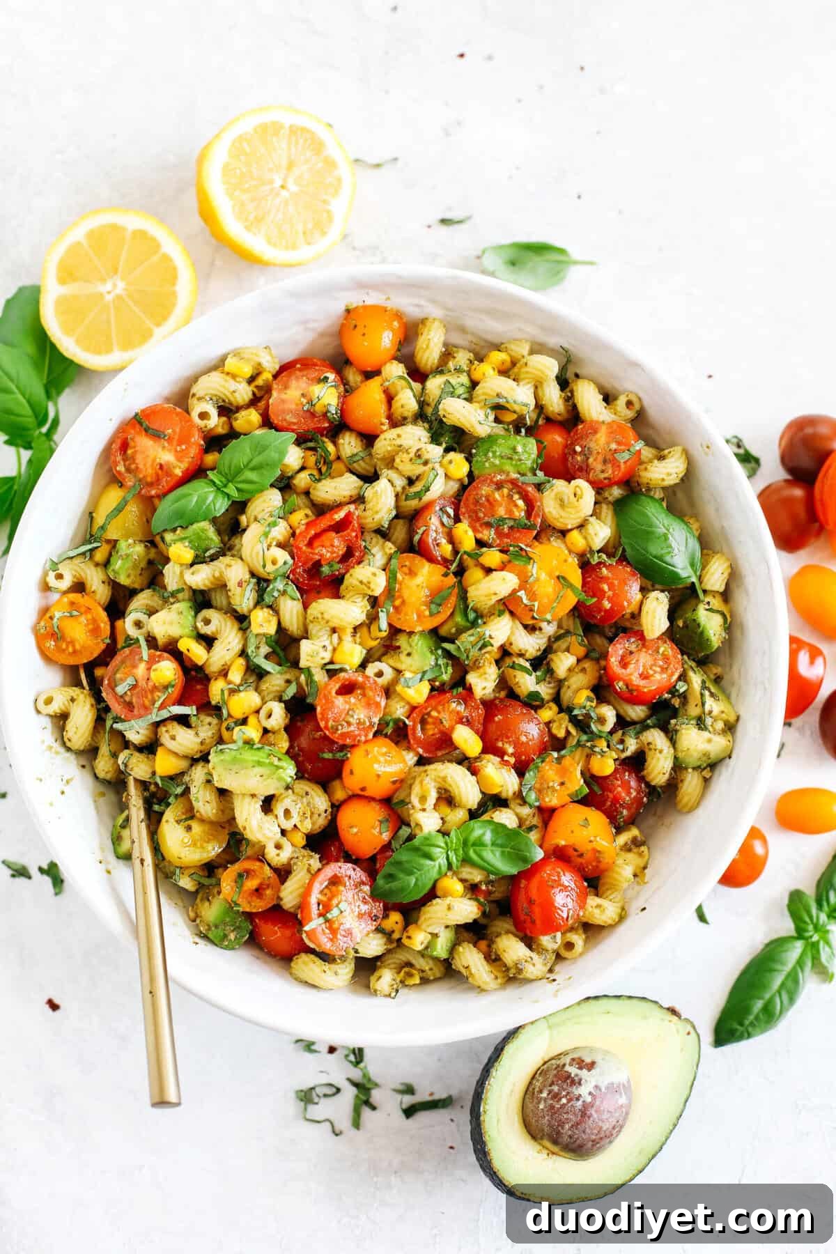 This EASY 10-minute Summer Pesto Pasta Salad is loaded with fresh ingredients like juicy tomatoes, corn, avocado, garlic, and lemon zest, all tossed together with warm pasta and delicious basil pesto!