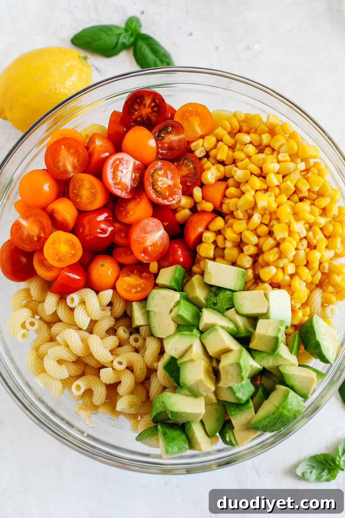 This EASY 10-minute Summer Pesto Pasta Salad is loaded with fresh ingredients like juicy tomatoes, corn, avocado, garlic, and lemon zest, all tossed together with warm pasta and delicious basil pesto!