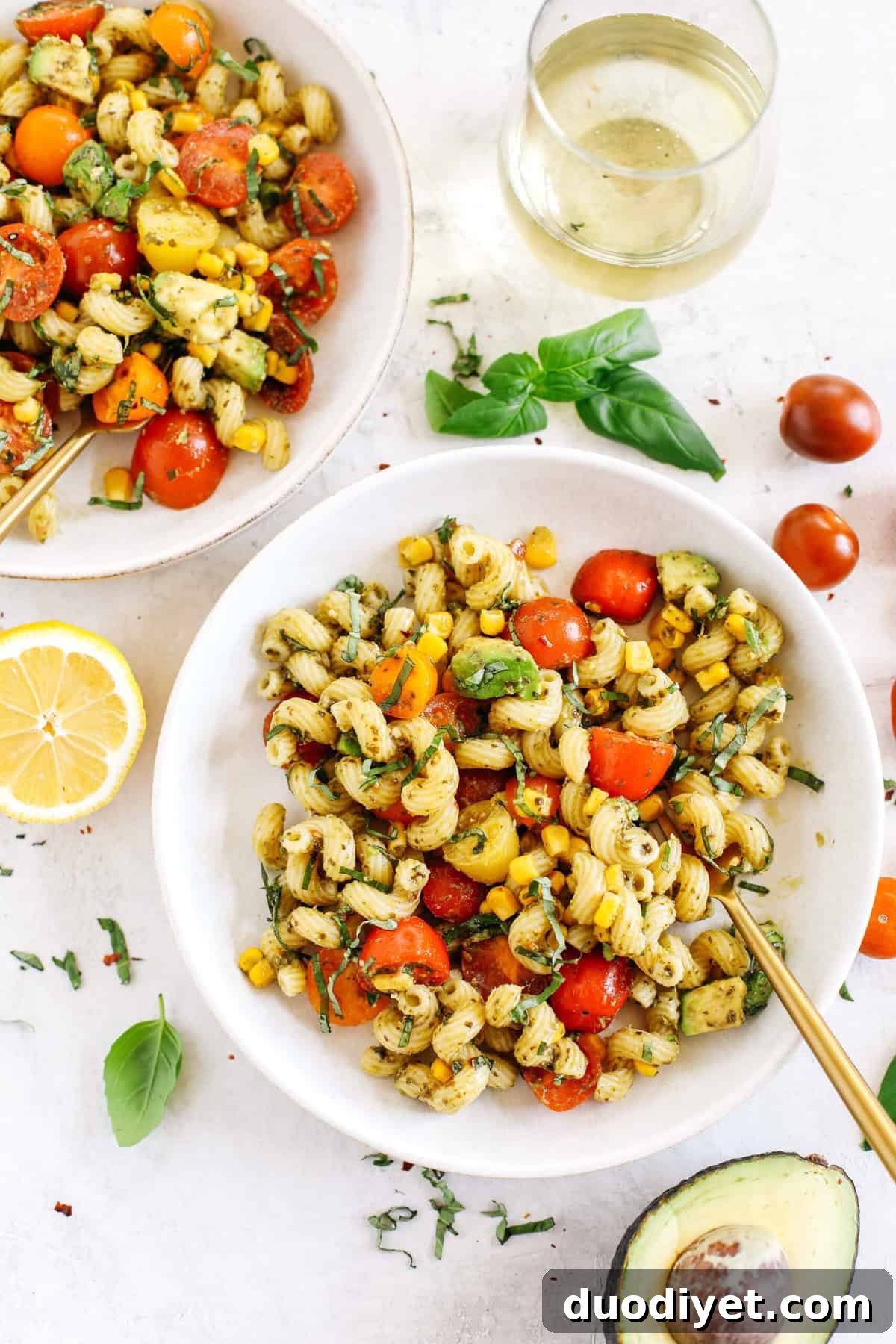 This EASY 10-minute Summer Pesto Pasta Salad is loaded with fresh ingredients like juicy tomatoes, corn, avocado, garlic, and lemon zest, all tossed together with warm pasta and delicious basil pesto!