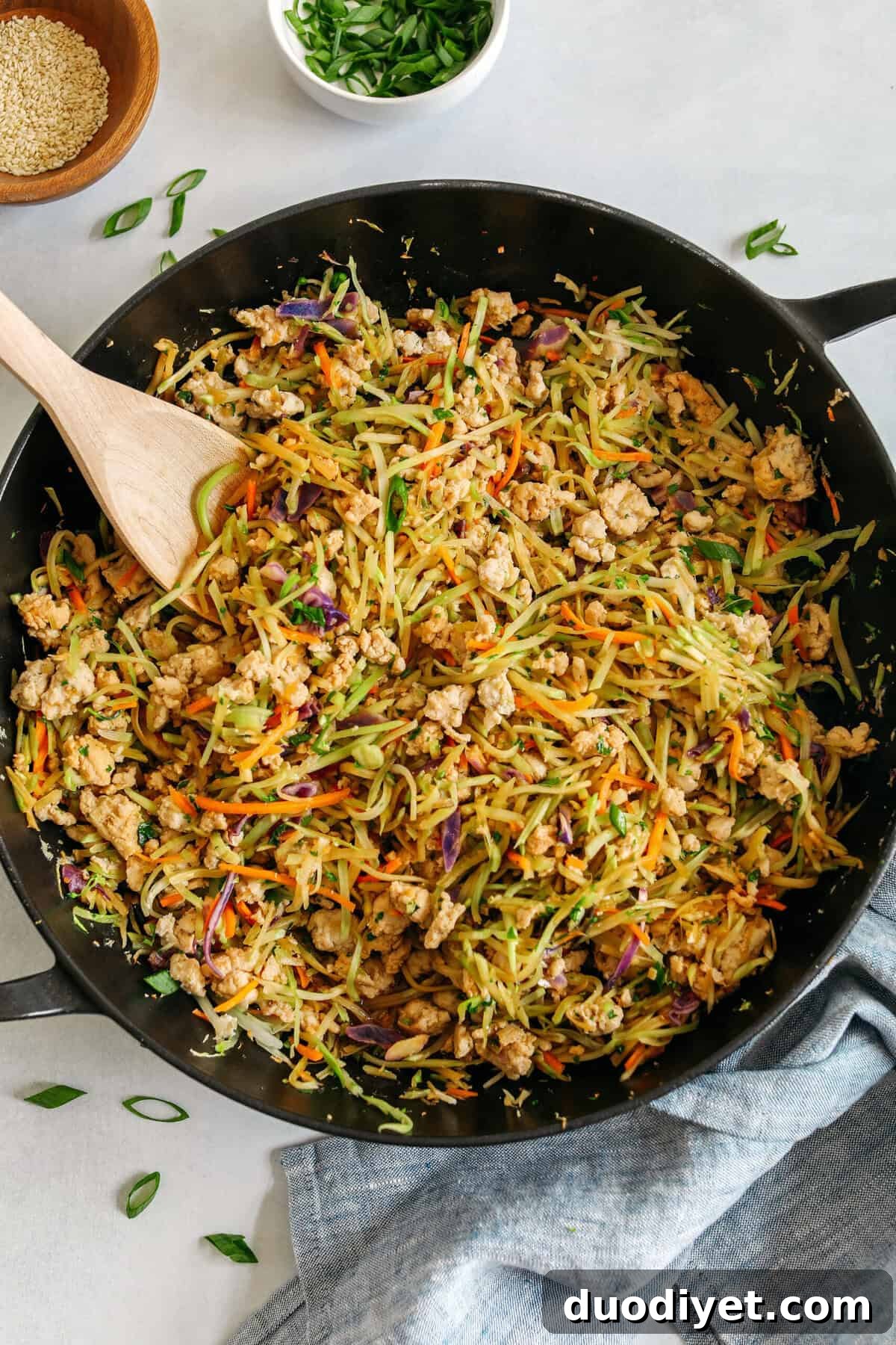 Chicken Egg Roll in a Bowl served over rice and garnished with green onions and sesame seeds.