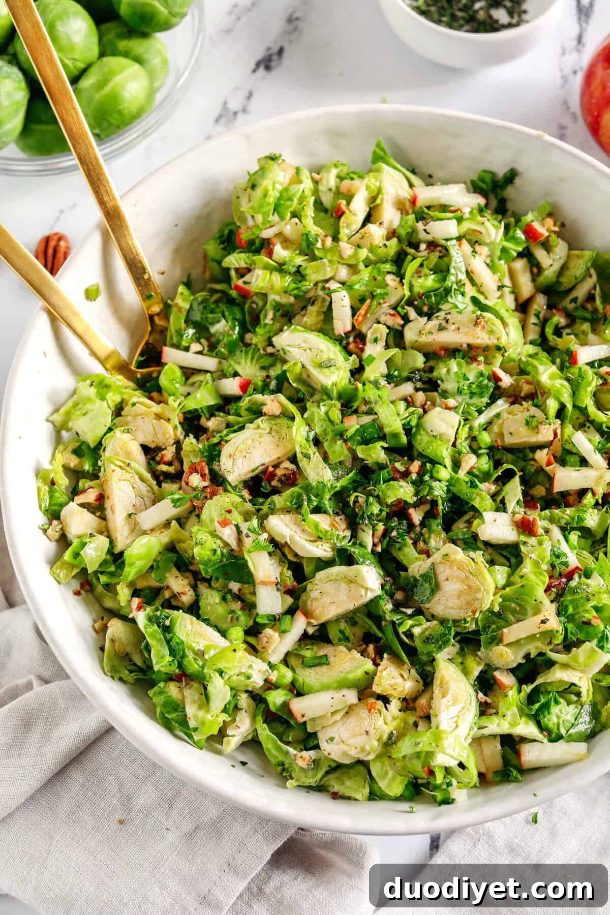 The most delicious Fall Brussels Sprout Salad made with shaved brussels sprouts, chopped apples and crunchy pecans all tossed with a maple dijon dressing!