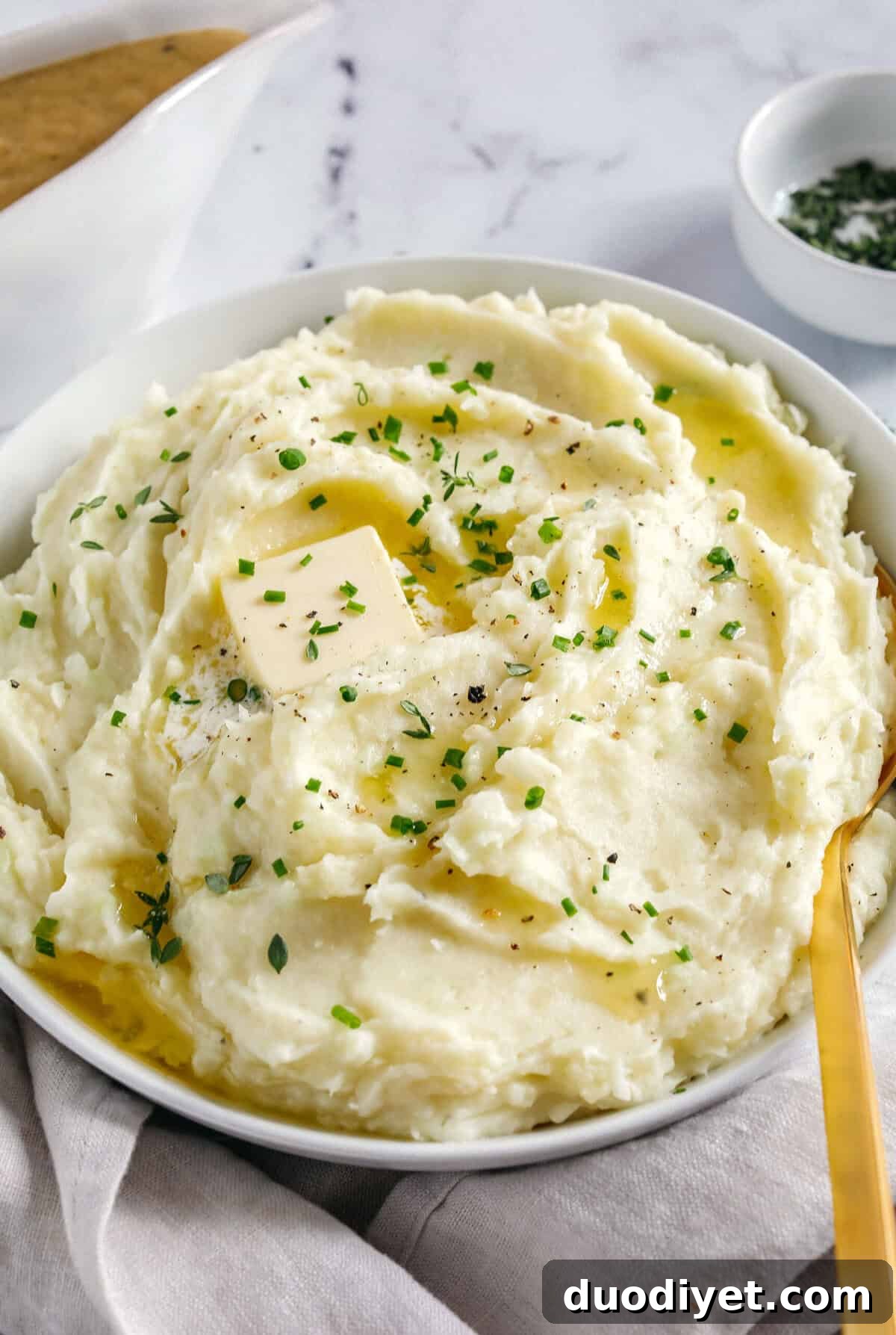 A bowl of creamy, lighter mashed potatoes with herbs