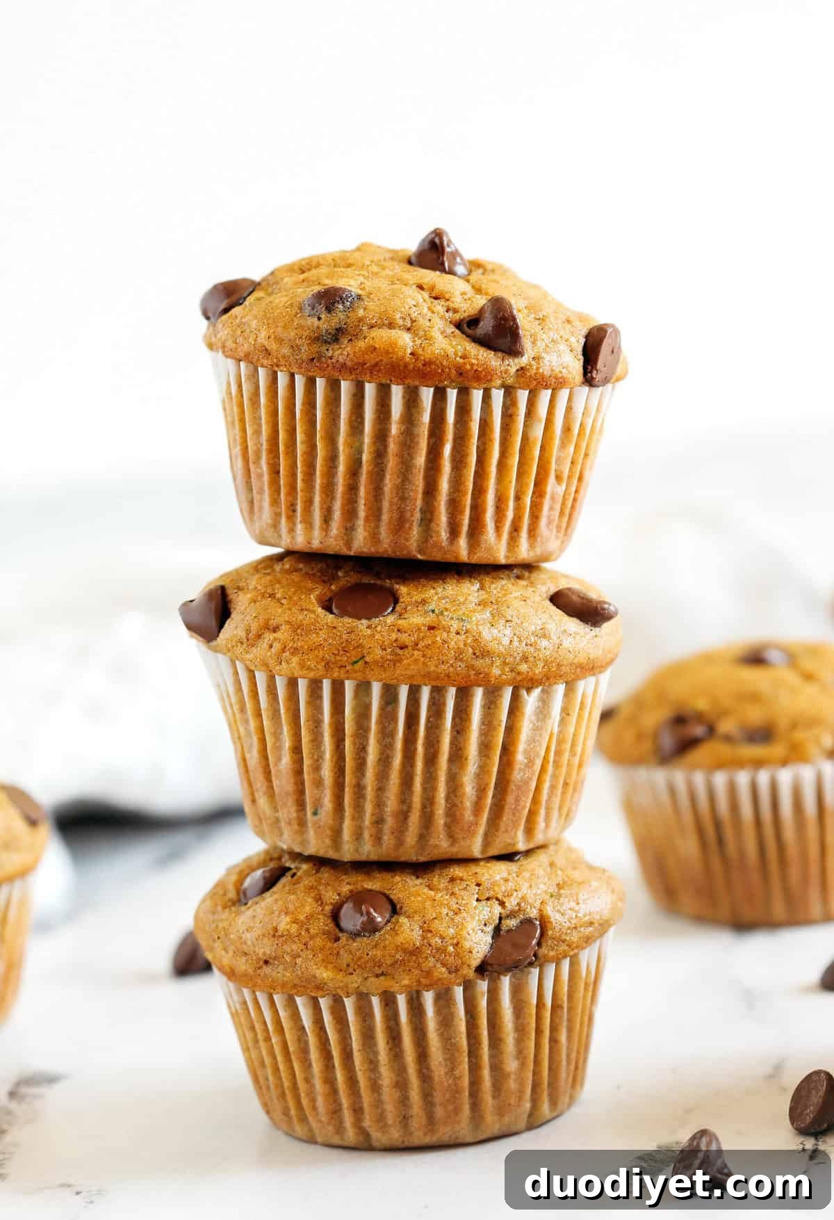 These Chocolate Chip Zucchini Muffins are moist, fluffy, and made healthier with whole wheat flour, Greek yogurt, shredded zucchini and zero butter or refined sugar.  Loaded with warm flavors and chunks of chocolate in every bite!