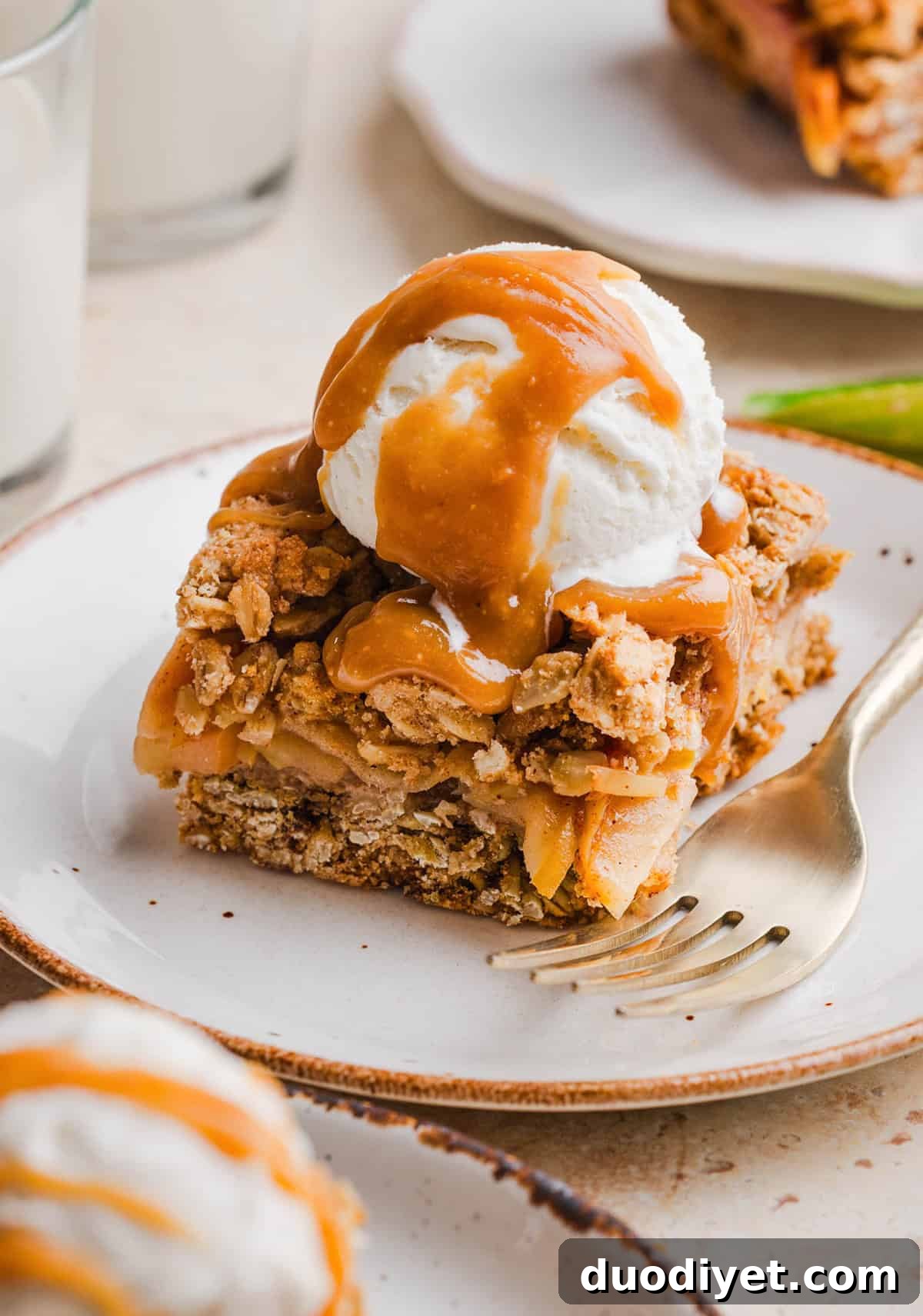 Healthy apple pie crumble bars topped with a scoop of vanilla ice cream and maple caramel drizzle.